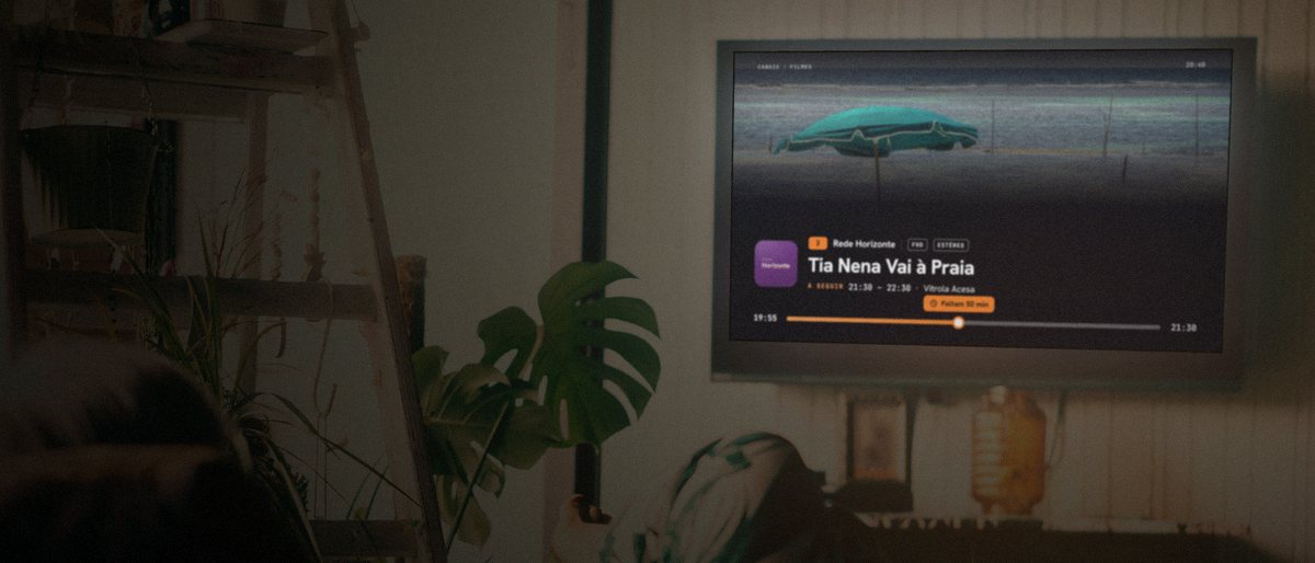 A mesma sala com o Modo Sênior ligado: na TV, as informações de Tia Nena Vai à Praia em letras grandes.